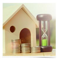 Toy house with coins and an hour glass