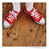 Red Converse on a wooden floor.