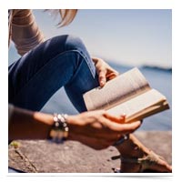 Woman reading a book on a dock.