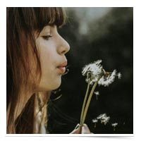 Young woman blowing a dandelion